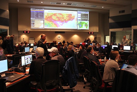 Emergency Management staff sitting at computers with a large screen in the background